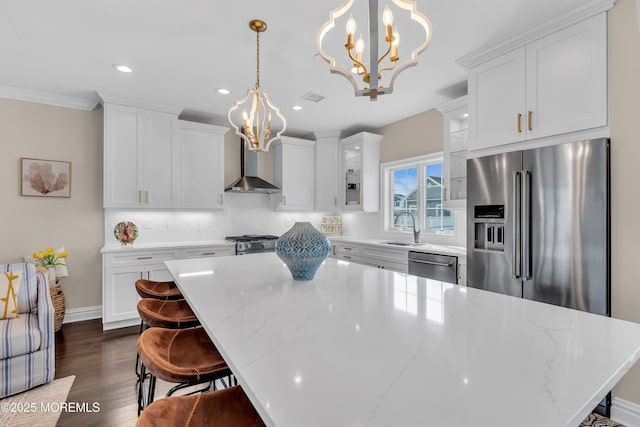 kitchen featuring decorative backsplash, appliances with stainless steel finishes, wall chimney exhaust hood, and white cabinets