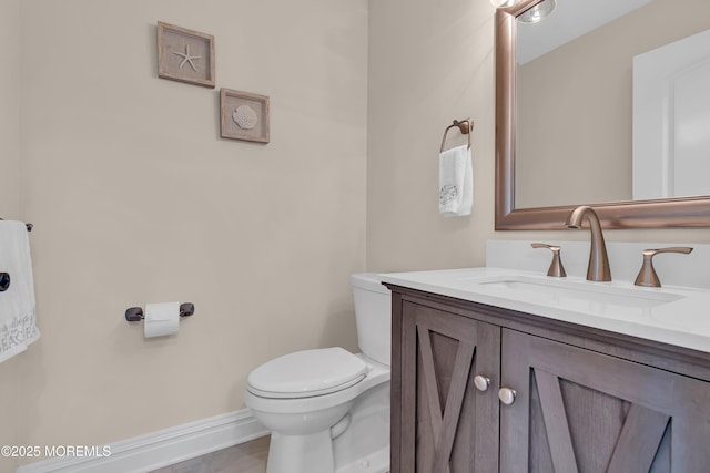 bathroom with baseboards, toilet, and vanity