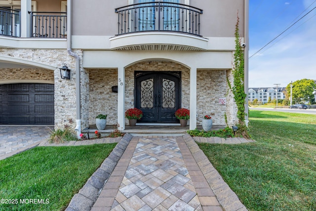 entrance to property featuring a lawn, french doors, a balcony, and stucco siding