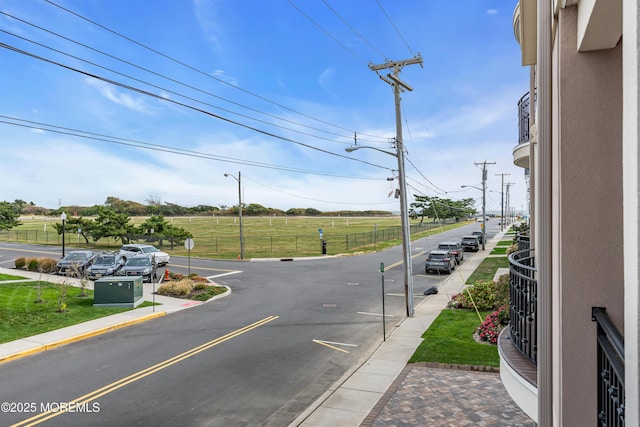 view of road featuring street lights, traffic signs, curbs, and sidewalks