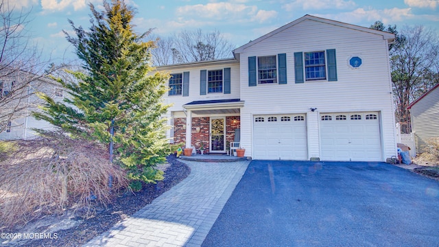 traditional home featuring aphalt driveway, brick siding, and a garage