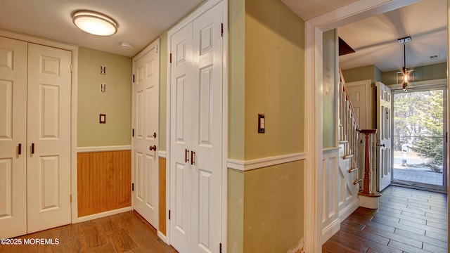 foyer entrance with a wainscoted wall, visible vents, and wood finished floors