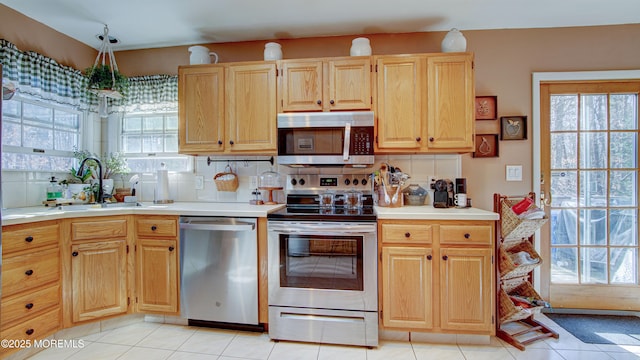 kitchen featuring stainless steel appliances, light countertops, and a healthy amount of sunlight