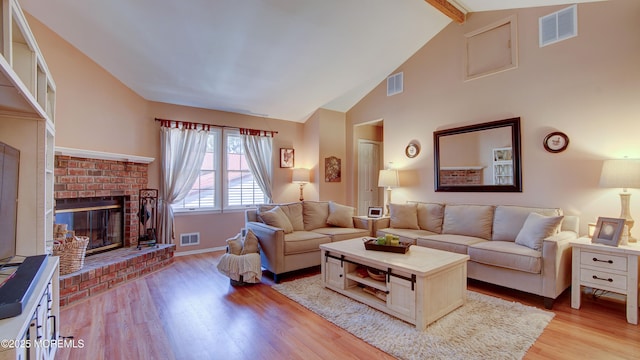 living room with a brick fireplace, visible vents, and light wood-style flooring