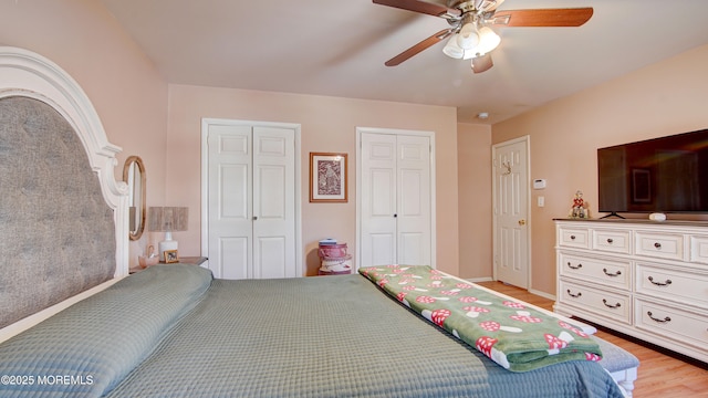 bedroom featuring multiple closets, light wood-type flooring, and ceiling fan