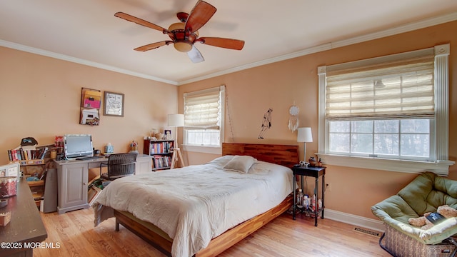 bedroom with light wood-style floors, visible vents, crown molding, and baseboards