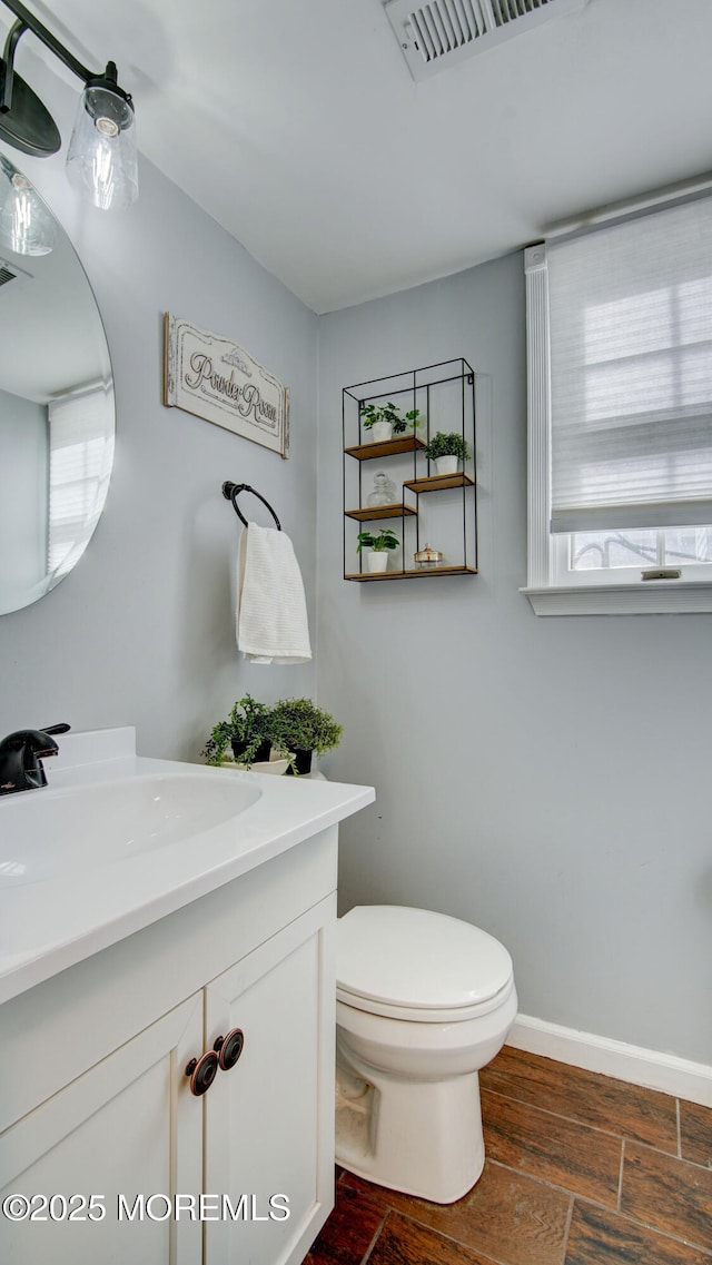 bathroom featuring visible vents, vanity, toilet, and baseboards