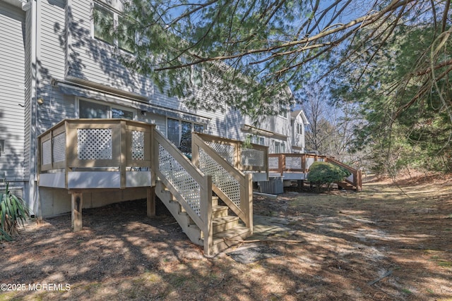 back of property with cooling unit, a wooden deck, and stairs