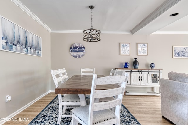 dining room with a chandelier, baseboards, light wood-style flooring, and crown molding