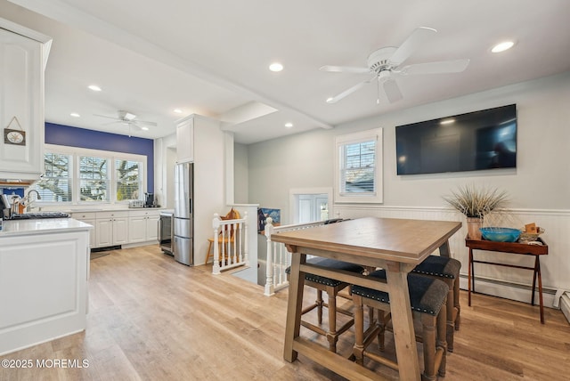 dining room featuring a wainscoted wall, light wood-style flooring, and a wealth of natural light