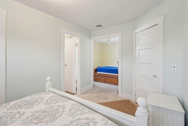 carpeted bedroom with visible vents, ensuite bath, and baseboards