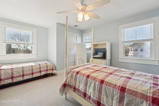 carpeted bedroom featuring baseboards, multiple windows, visible vents, and a ceiling fan