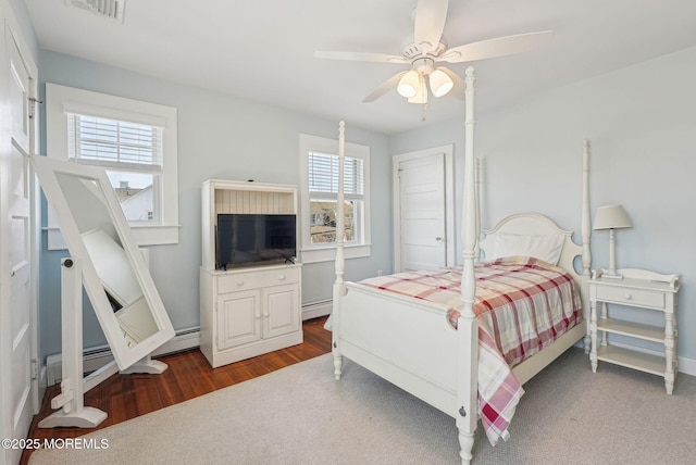 bedroom featuring ceiling fan, baseboard heating, wood finished floors, and visible vents