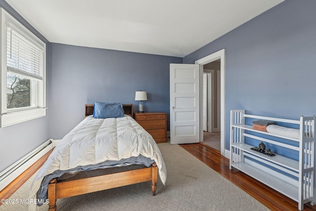 bedroom featuring a baseboard heating unit and wood finished floors