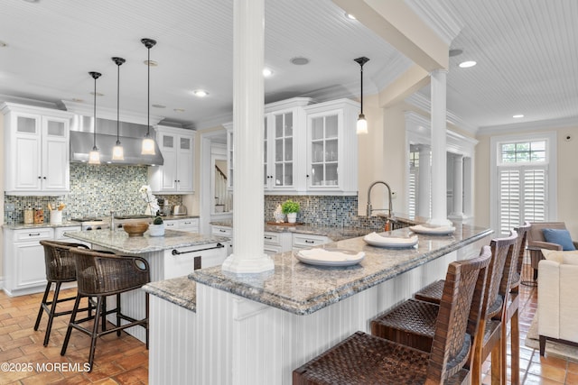 18 Riverdale Ave, Monmouth Beach, NJ 07750 - kitchen featuring crown molding, decorative columns, a breakfast bar, white cabinetry, and decorative backsplash