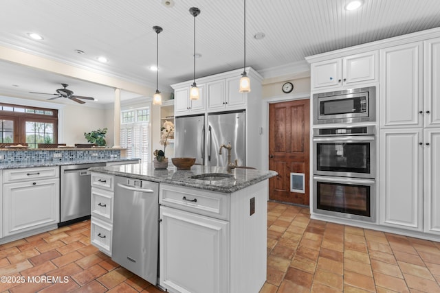 18 Riverdale Ave, Monmouth Beach, NJ 07750 - kitchen featuring appliances with stainless steel finishes, a center island with sink, a sink, crown molding, and white cabinetry