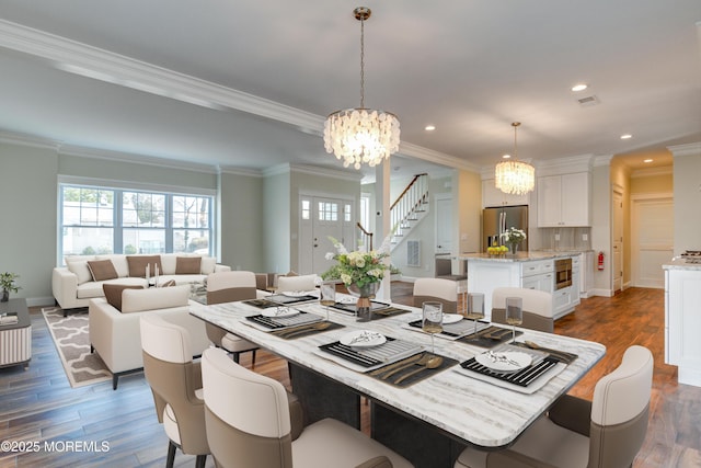 dining area with dark wood-style flooring, ornamental molding, a chandelier, recessed lighting, and stairway