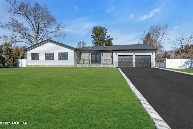 view of front of property with a front yard, fence, a garage, stone siding, and driveway