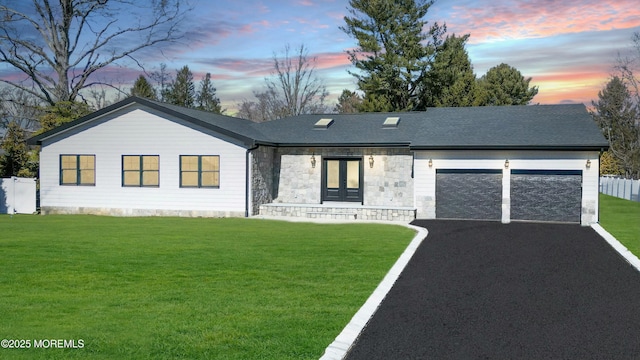 ranch-style home featuring a garage, aphalt driveway, roof with shingles, french doors, and a front lawn