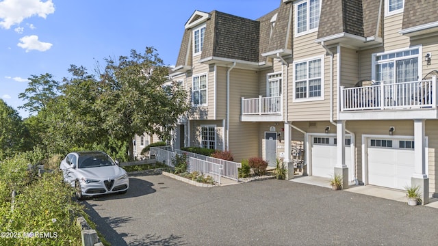 view of front of house with a shingled roof, mansard roof, and aphalt driveway