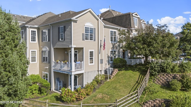 view of side of home featuring a lawn and fence