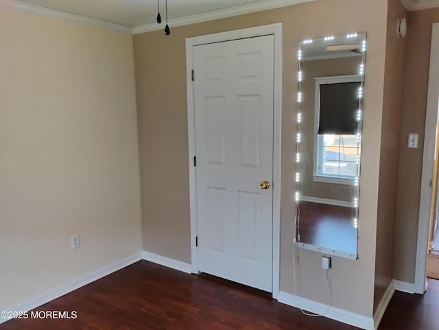 interior space featuring dark wood-type flooring, ornamental molding, and baseboards