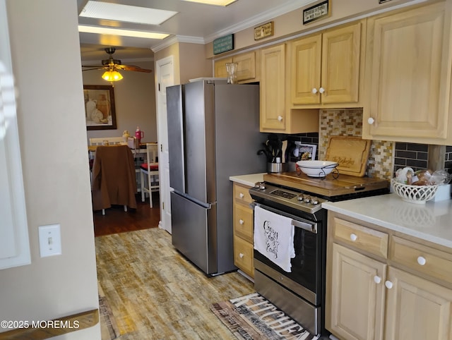 kitchen with light countertops, ornamental molding, appliances with stainless steel finishes, light wood-type flooring, and backsplash