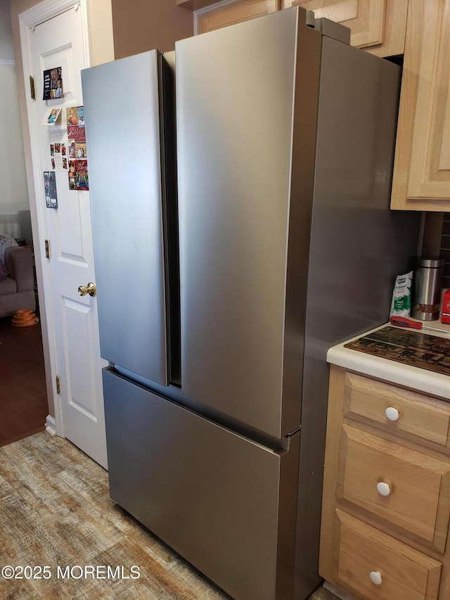 kitchen with light brown cabinetry, light wood-type flooring, and freestanding refrigerator