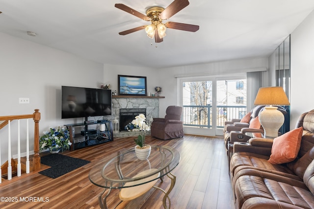 living area featuring ceiling fan, a fireplace, and wood finished floors