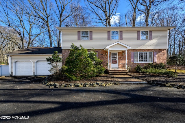 colonial-style house with entry steps, brick siding, driveway, and an attached garage