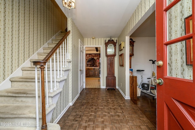 foyer with baseboards, stairway, parquet flooring, and wallpapered walls