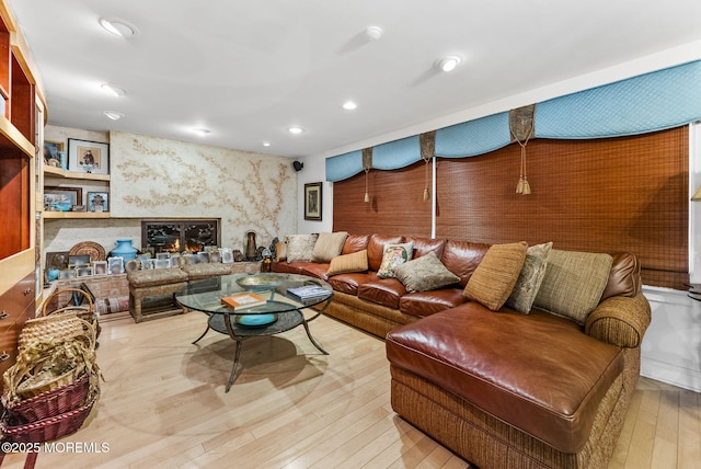 living area with a premium fireplace, hardwood / wood-style floors, and recessed lighting