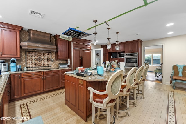 kitchen featuring paneled built in fridge, visible vents, a kitchen island, custom range hood, and backsplash