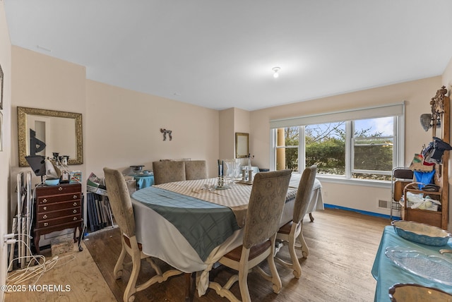 dining space featuring baseboards, visible vents, and light wood-style floors