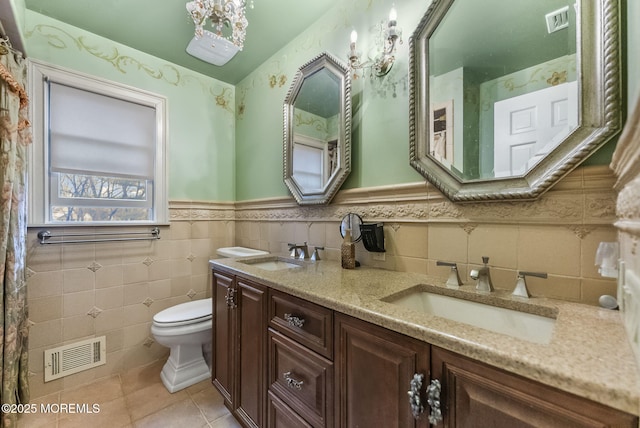 bathroom with toilet, a sink, and visible vents