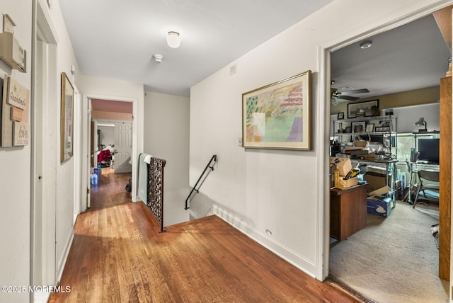 corridor with baseboards, wood finished floors, and an upstairs landing