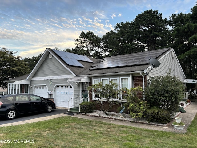 view of front facade featuring an attached garage, brick siding, concrete driveway, roof mounted solar panels, and a front lawn