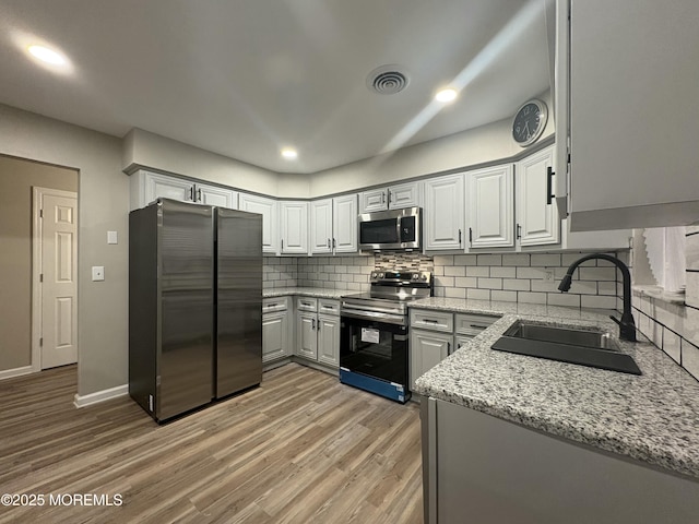 kitchen with tasteful backsplash, visible vents, appliances with stainless steel finishes, light wood-style floors, and a sink