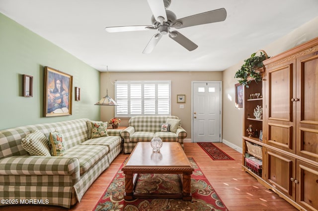 living room featuring ceiling fan, baseboards, and wood finished floors