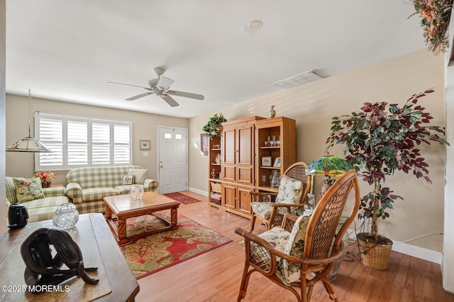 living room featuring ceiling fan, wood finished floors, visible vents, and baseboards