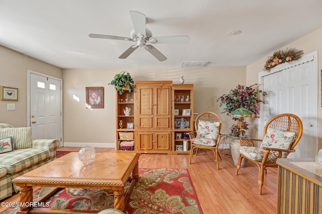 living room featuring light wood-type flooring, baseboards, visible vents, and a ceiling fan