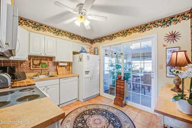 kitchen with light tile patterned floors, white appliances, a sink, white cabinetry, and decorative backsplash