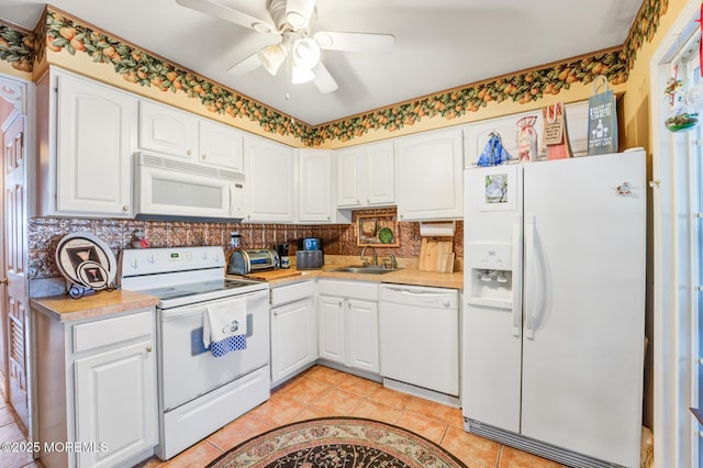 kitchen featuring light tile patterned floors, white appliances, a sink, light countertops, and tasteful backsplash