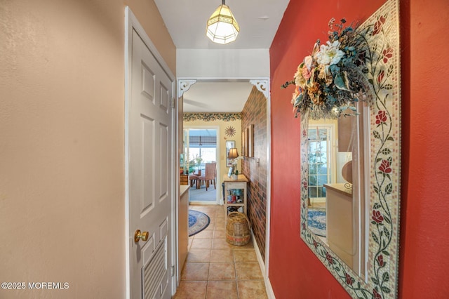 hall featuring arched walkways and light tile patterned flooring