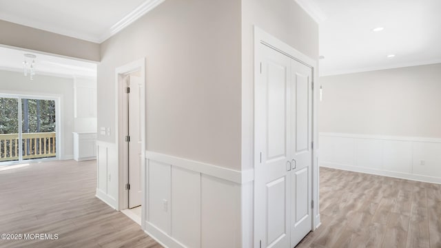 corridor with ornamental molding, light wood-type flooring, a wainscoted wall, and recessed lighting