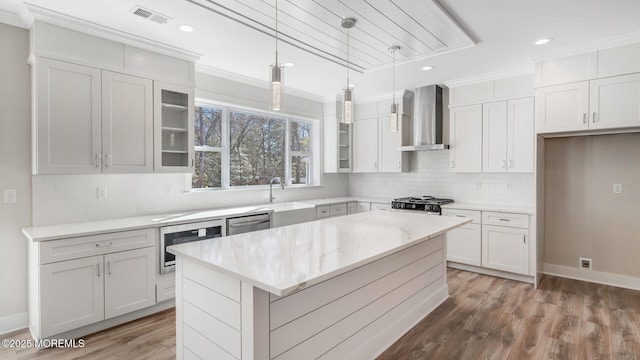 kitchen featuring stove, a center island, a sink, wall chimney range hood, and stainless steel dishwasher