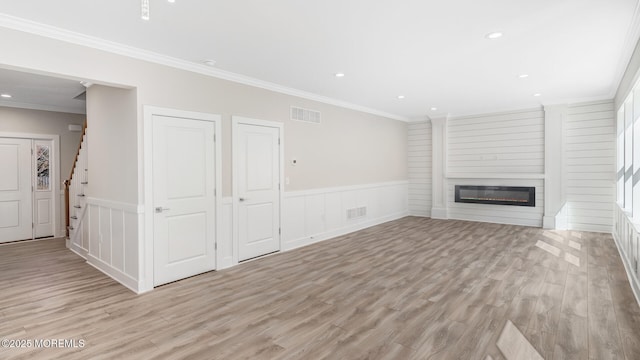 unfurnished living room with a wainscoted wall, visible vents, a fireplace, and stairway