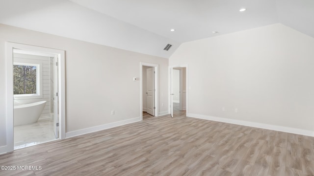 unfurnished bedroom with light wood-style floors, visible vents, vaulted ceiling, and baseboards