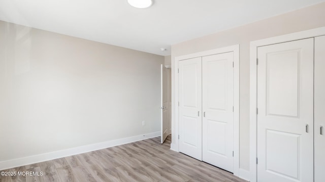 unfurnished bedroom featuring light wood-type flooring, a closet, and baseboards