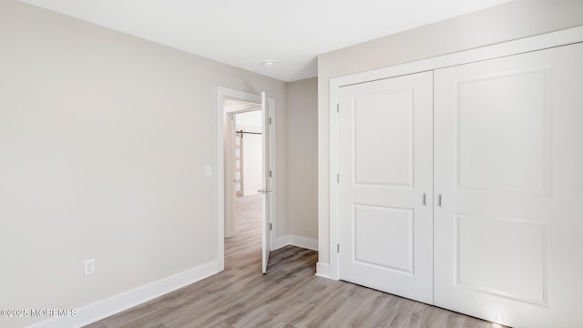 unfurnished bedroom with light wood-style floors, baseboards, and a closet